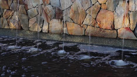 sunlight on urban rock wall water fountain helps create serene calm