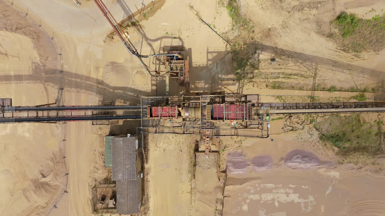 Overhead aerial drone footage of heavy plant machinery and conveyor systems in aggregates quarry Rugby England UK