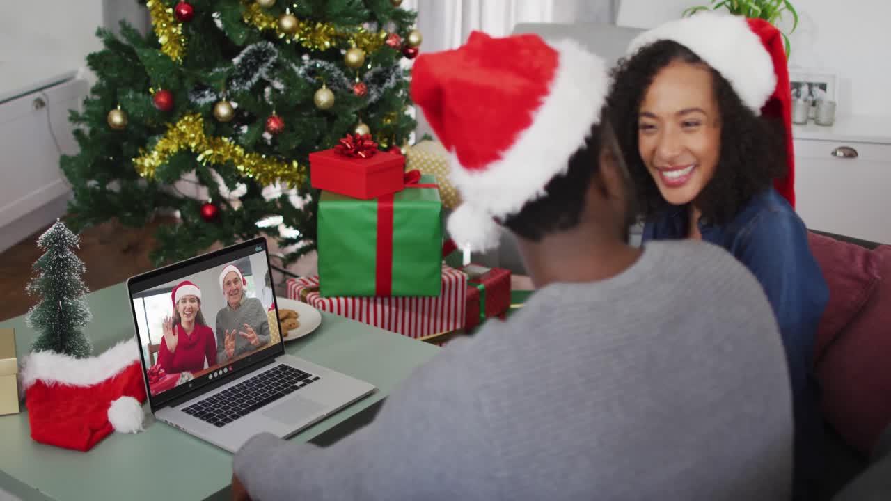 feliz pareja afroamericana en videollamada en computadora portátil con amigos en tiempo de navidad