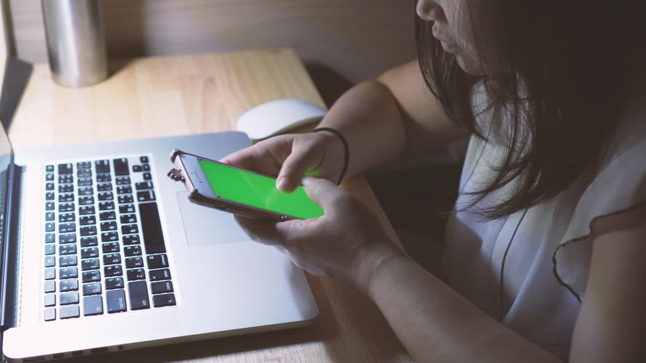 Woman using smartphone with green screen display