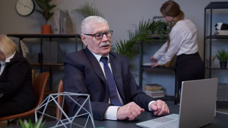 portrait of bored, tired business man using laptop making online work sits at office desk workplace