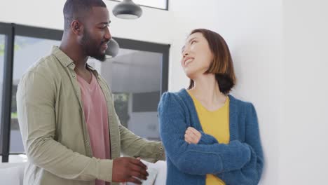 video of happy diverse couple smiling at each other and embracing at home