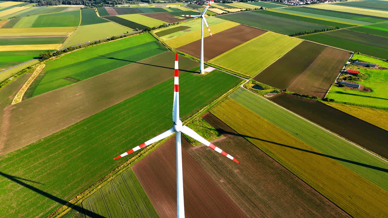 Windmill blades rotate in the field. Aerial view on the wind turbine in the agricultural countryside.