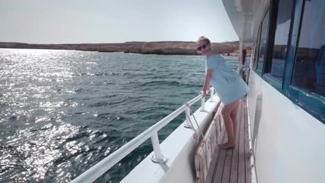 portrait of a young beautiful sexy caucasian woman on a yacht in in a blue dress and sunglasses. the concept of vacation, freedom, sunny summer. blue ocean on backgroung. steadycam