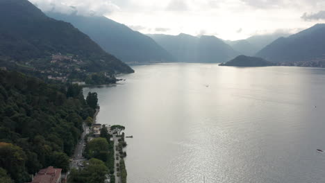 aerial overview of a vast and beautiful lake near a green shoreline with a long road