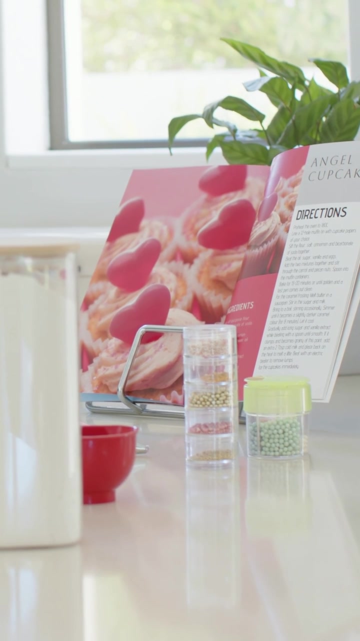 Vertical video: Panning camera revealing cookbook, sprinkles on kitchen counter, showing Directions