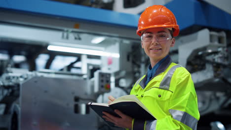 trabajadora de una fábrica que busca una cámara cerca de grandes construcciones de fabricación de metal.
