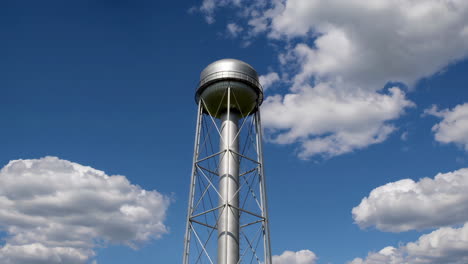 silver water tower against a blue sky with clouds