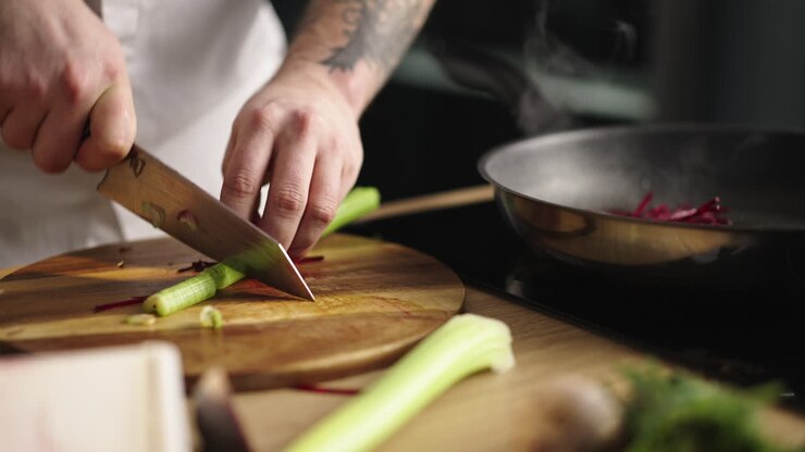 Chef che prepara sedano e altri ingredienti in cucina