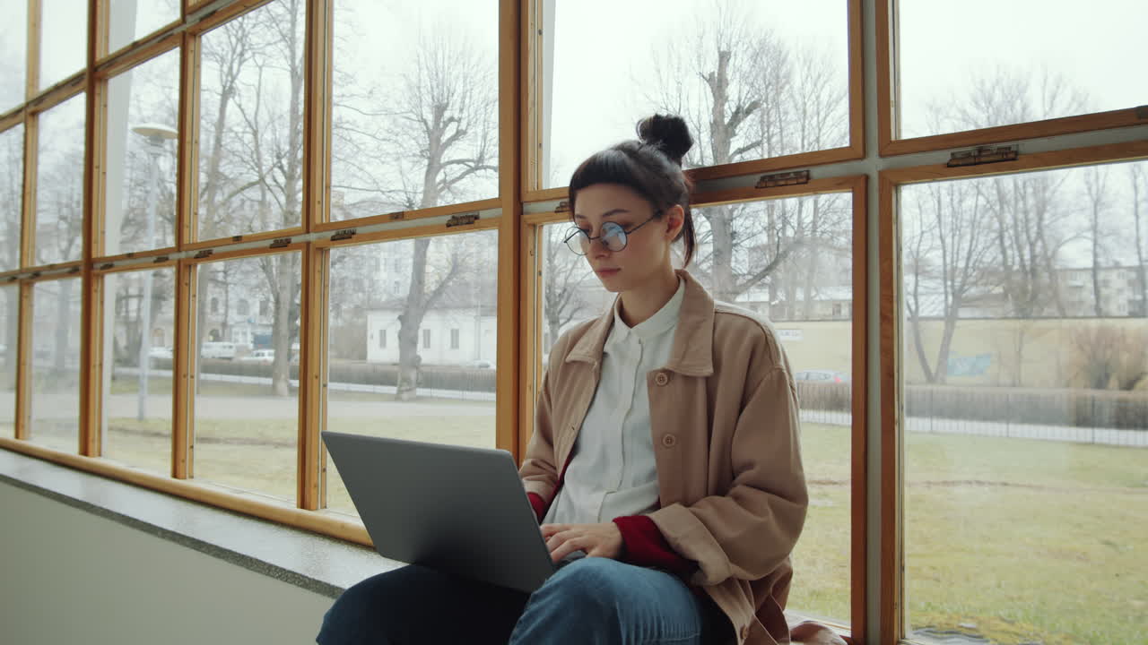Young Woman Using Laptop and Smiling at Camera