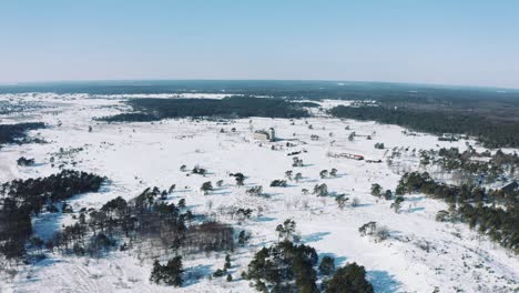 Vista-Aérea-De-Los-Países-Bajos-Rurales-En-El-Soleado-Día-De-Invierno,-La-Tierra-Cubierta-De-Nieve-Y-El-Horizonte-En-La-Catedral-De-Radio-Kootwijk-En-El-Parque-Nacional-De-Veluwe