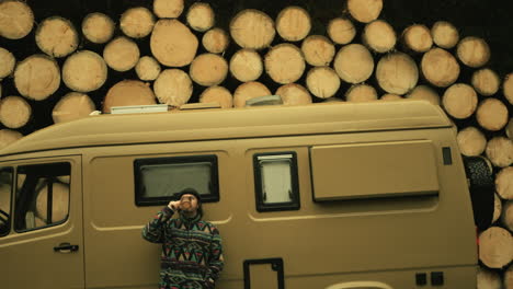 man drinking coffee near camper van in forest