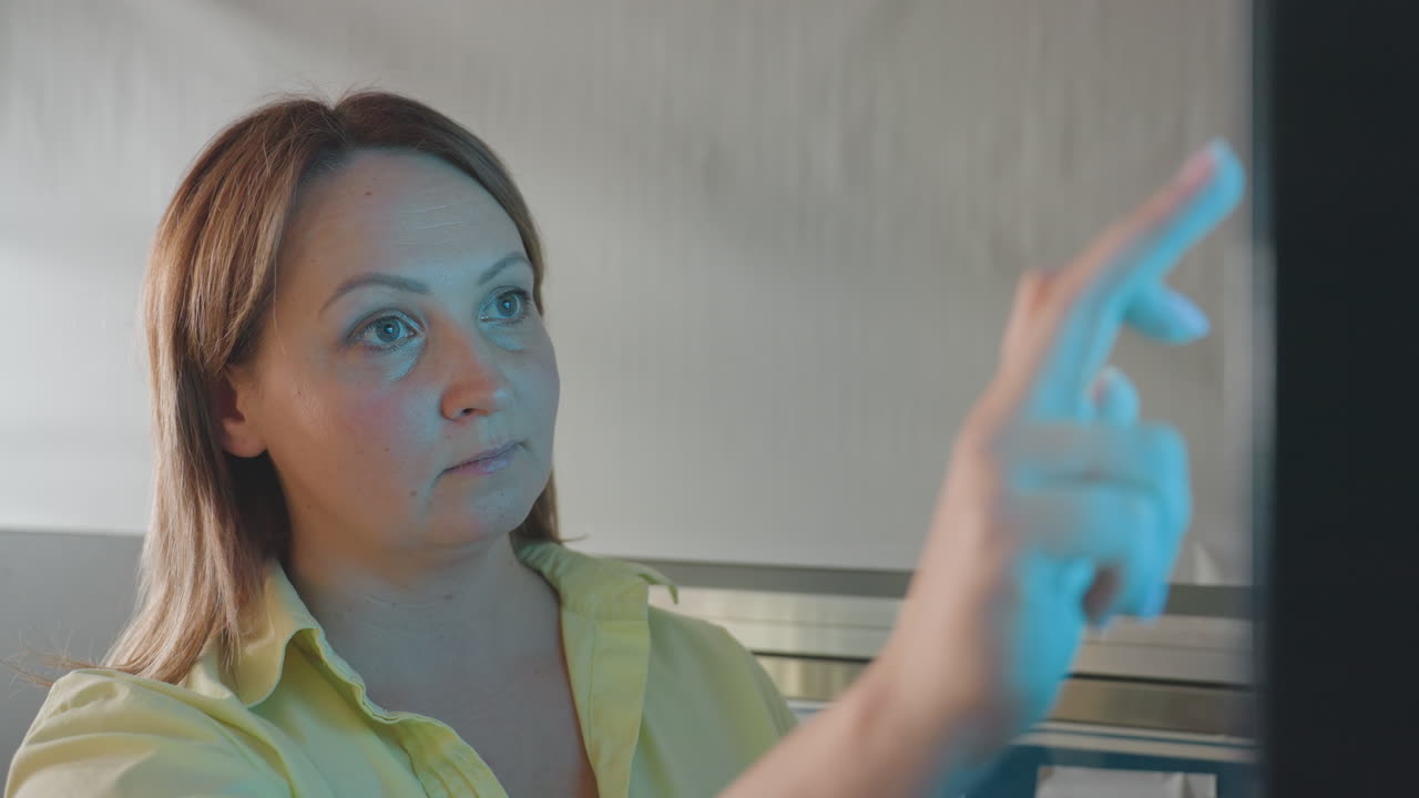 Close up face of female entrepreneur at payment kiosk, finger touching screen selecting wash program, focused expression,self service technology, contactless interaction, indoor transaction moment