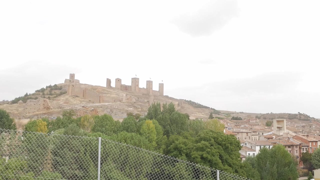 Sentiero che conduce da un edificio moderno a un castello storico in cima a una collina con vista su Molina de Aragón.