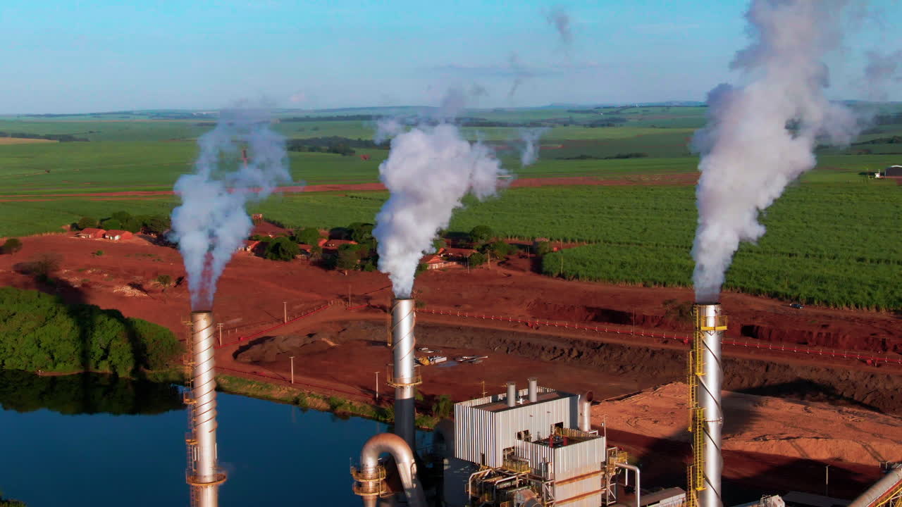 Drone aerial landscape of steam coming from steel turbines at ethanol production plant factory facility with distillation and fermentation process in Brazil countryside farmland industry production
