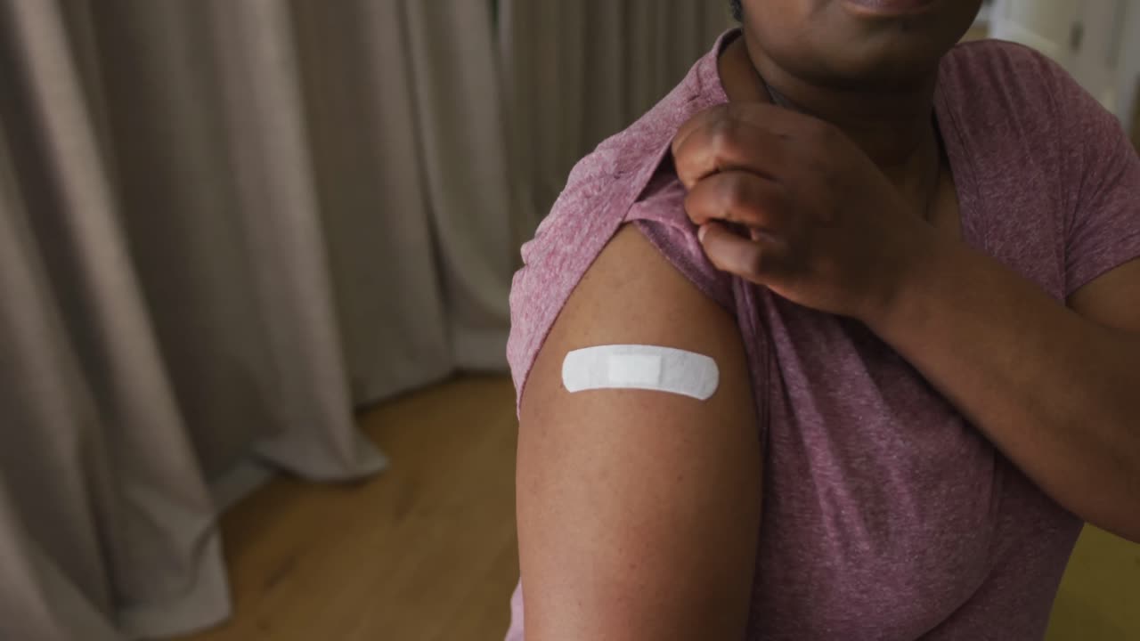 African american man showing plaster on arm where he was vaccinated against coronavirus