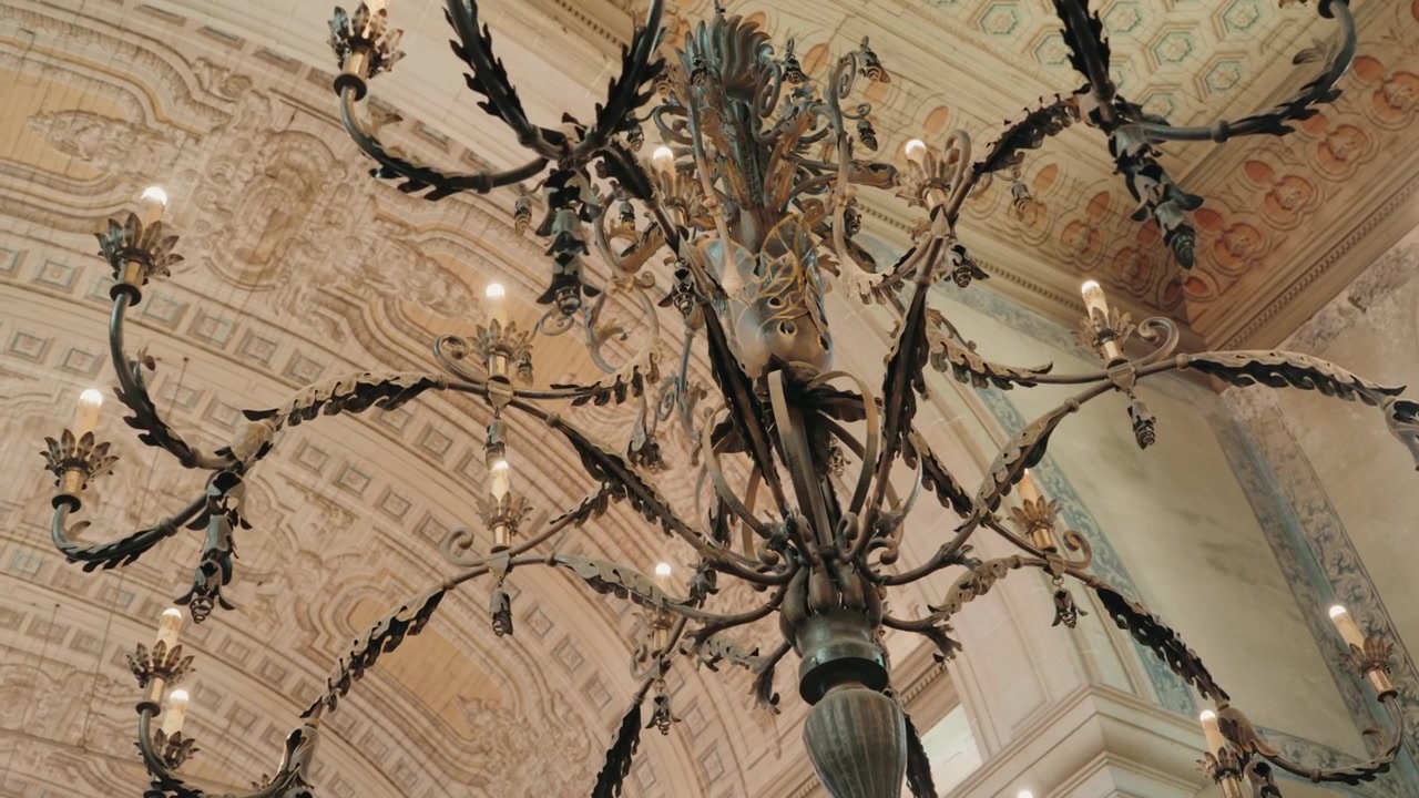 Grande lustre antigo de ferro pendurado sob um teto abobadado com afrescos em um palácio em Portugal