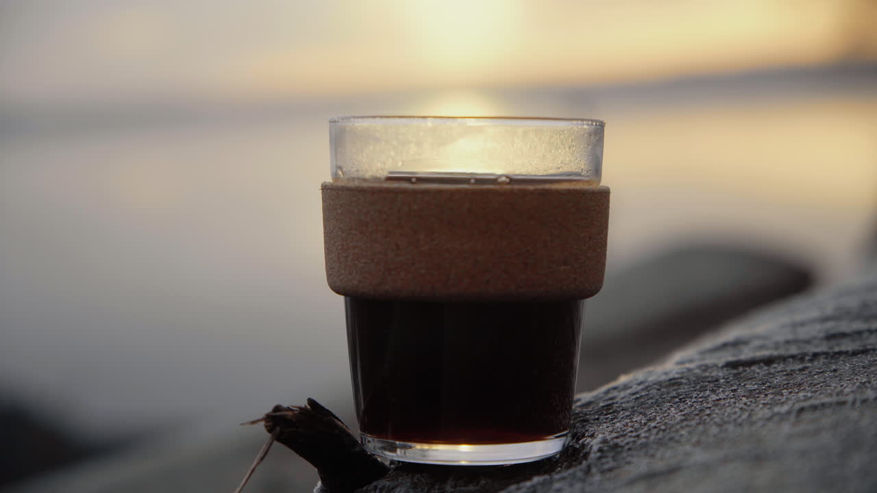 아침 해가 뜨면 나무에 놓인 유리잔에 담긴 지속 가능한 컵에 든 커피