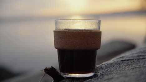 café en una taza de vidrio sostenible colocada en un árbol al amanecer por la mañana