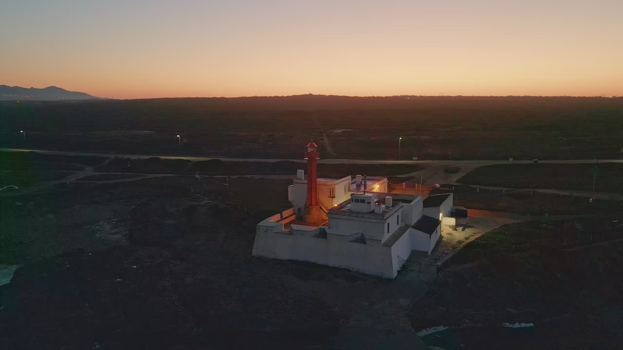 Lighthouse blinking ocean coast at summer evening aerial view. Coastal sunset