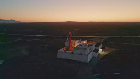 lighthouse blinking ocean coast at summer evening aerial view. coastal sunset