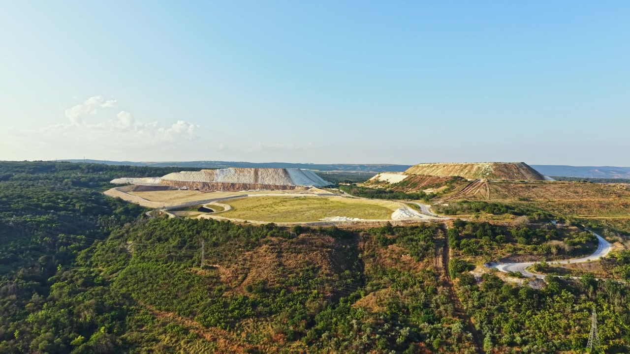 Vista de uma grande área aberta com colinas e vegetação durante o dia, mostrando mudanças no uso da terra e na paisagem em um ambiente externo.
