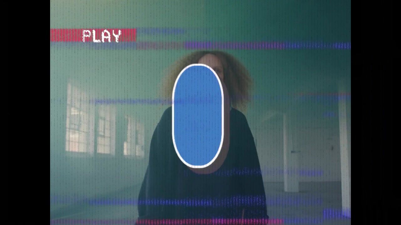 Vertical video: Standing woman in dark top in studio PLAY showing likes cycling counts revealing
