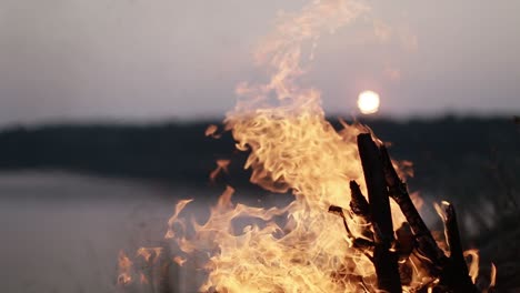 Campfire Burns Brightly At Sunset. Campfire burns brightly at sunset along the beautiful beach of lake