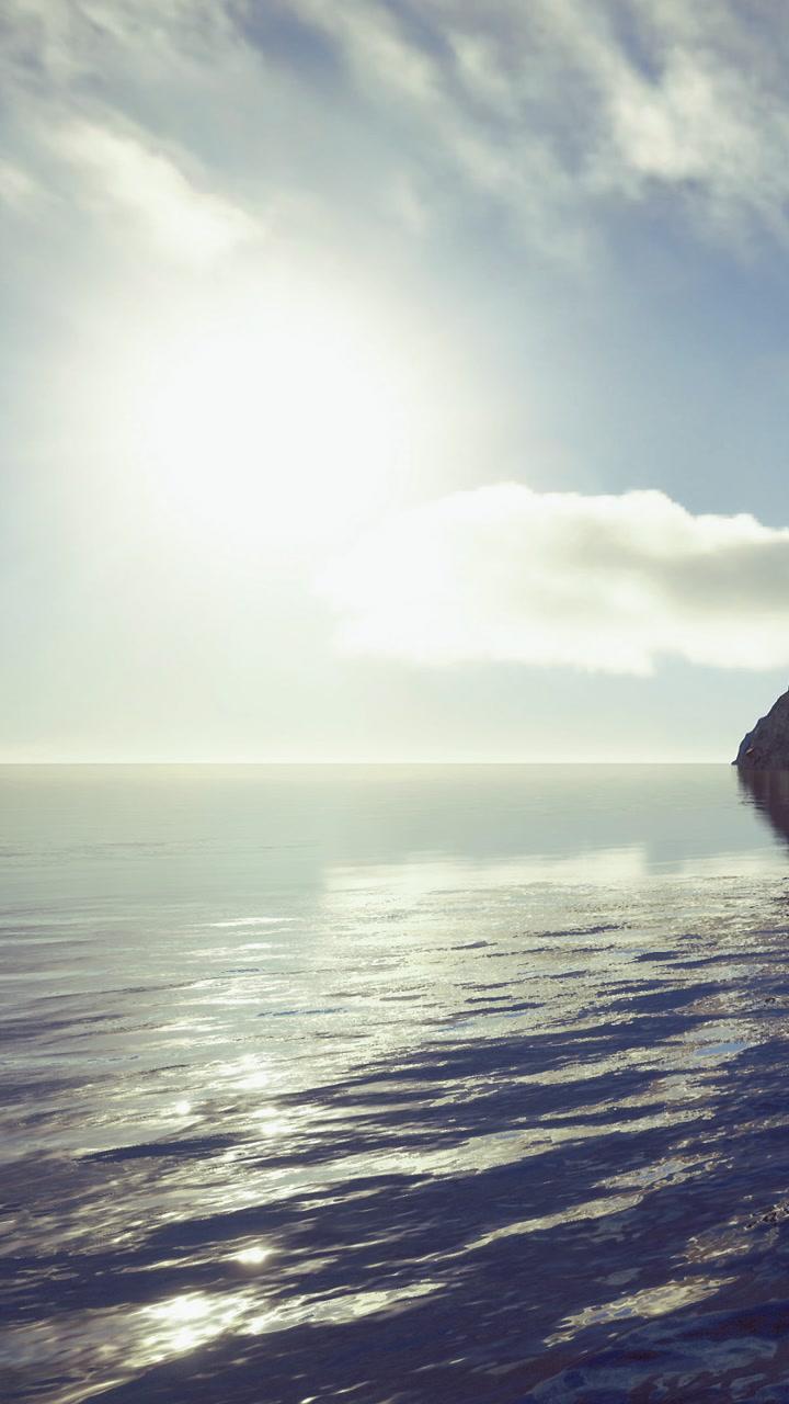 Sunshine reflects on calm water near rocky shore at midday