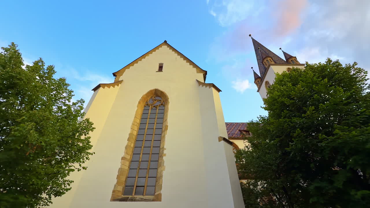 Back view of Lutheran Cathedral in Sibiu. Tall gothic windows of the Lutheran Cathedral with trees around in Sibiu