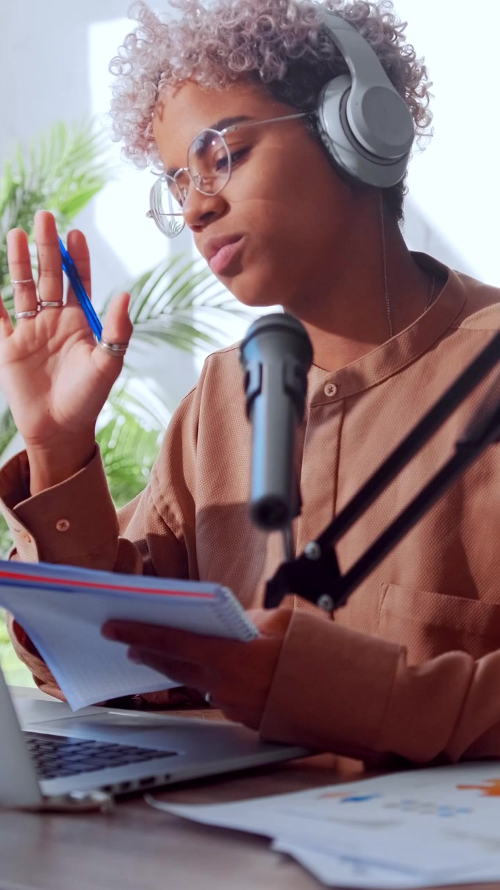 Young african american woman in glasses and headphones writes in her notebook