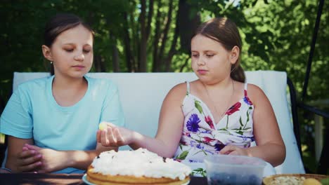 two girls enjoying dessert outdoors with cake and fresh berries on a sunny day