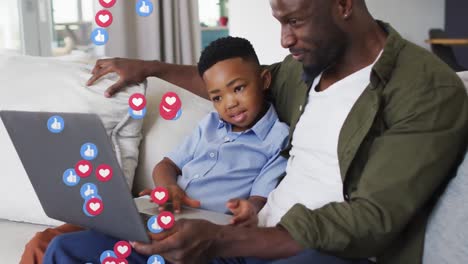 Animation-of-emoticons-over-happy-african-american-father-and-son-using-laptop