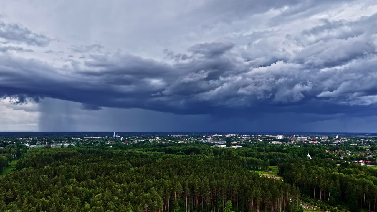 A realtime aerial shot of Jelgava, Latvia shows dense forests and the city beneath dramatic storm clouds