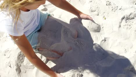 chica jugando con arena en la playa