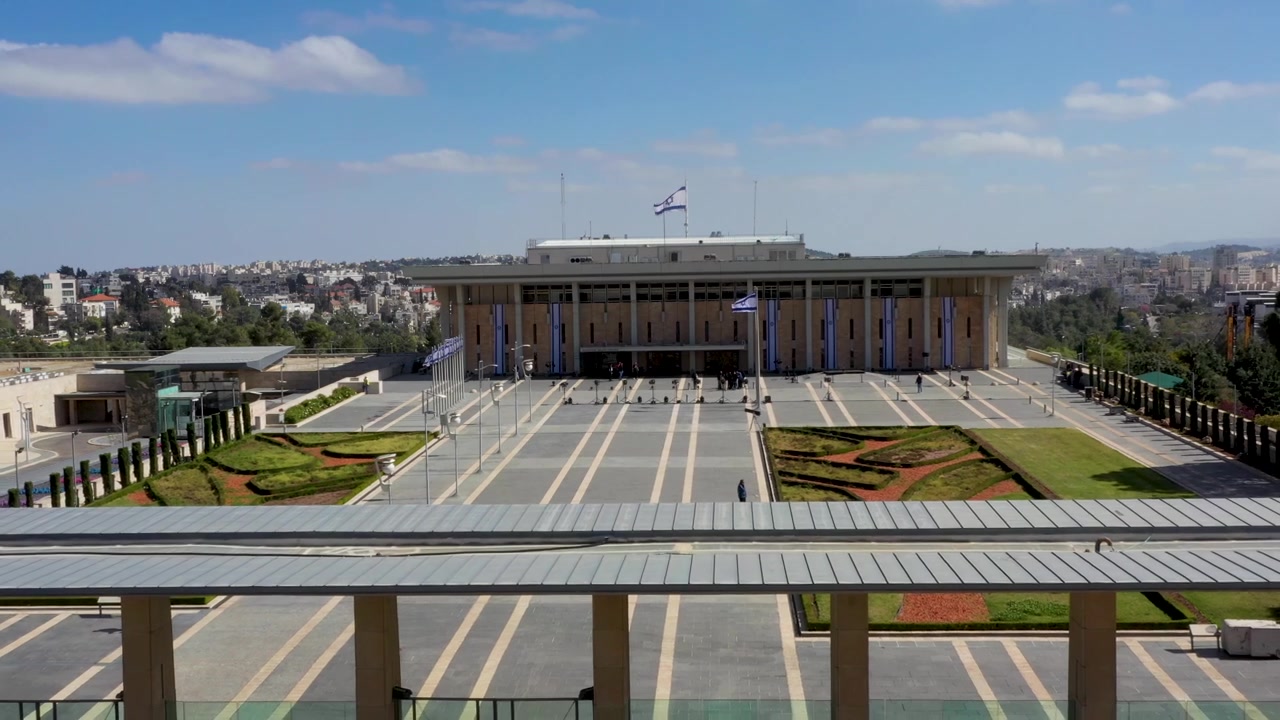 Perspectiva de ángulo alto del edificio del parlamento israelí, banderas nacionales y plaza ajardinada a la luz del día, Jerusalén.