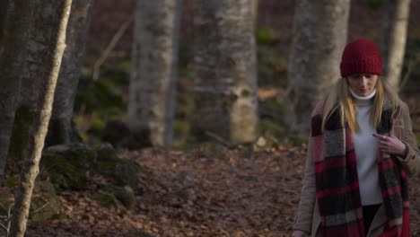 young caucasian woman walks in woods with book in hand