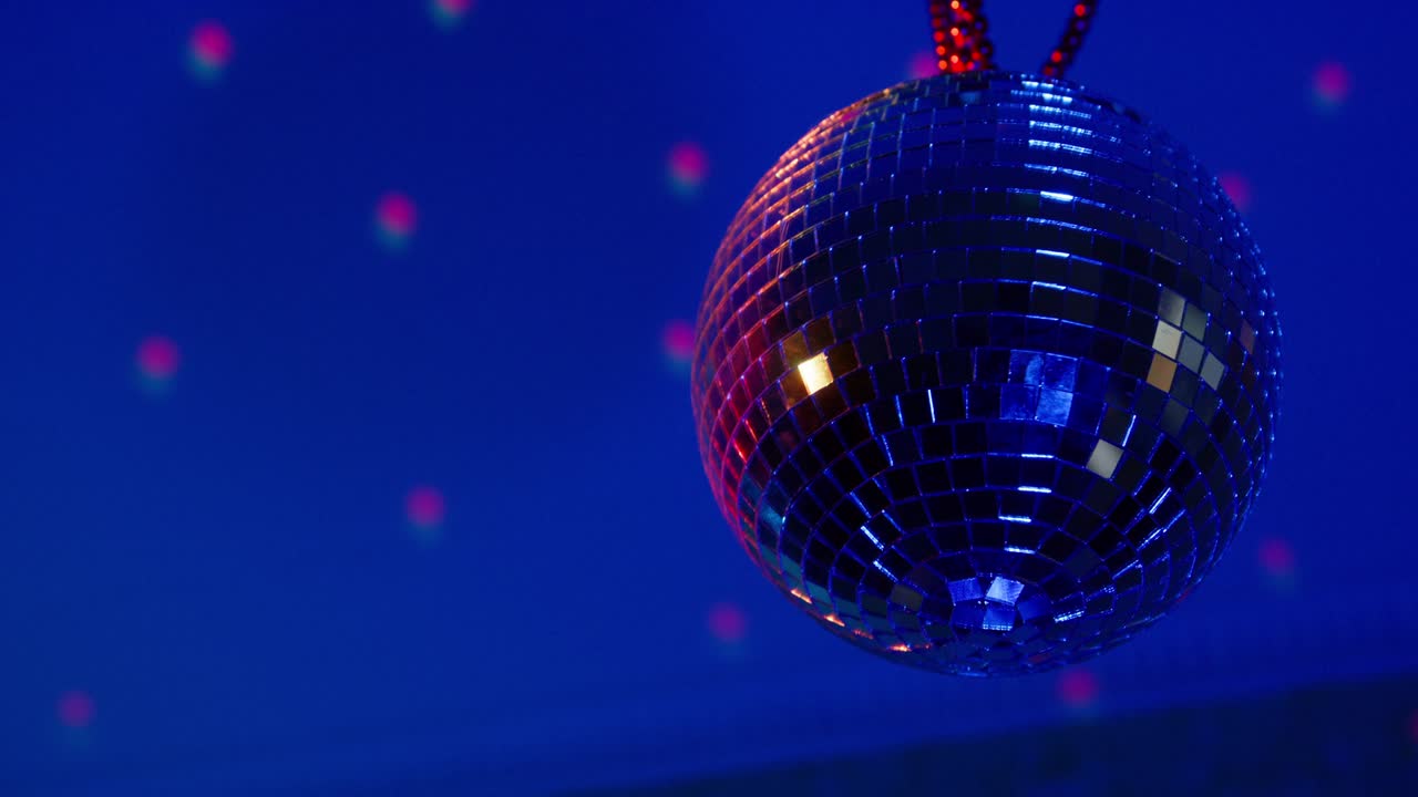 bola de discoteca brillante con pequeñas placas de espejo gira colgando en el techo en el cambio de colores luces en la sala cerca de bajo ángulo de disparo