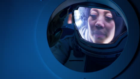 astronaut in space suit looking out a window