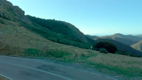 Aerial-view-from-Parco-del-Beigua-Geopark-sign,-revealing-shaded-hills,-panoramic-sunset-lit-mountains