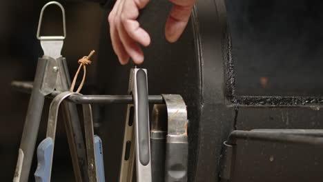 bbq pit lid opens and smoke pours out while man grabs tongs