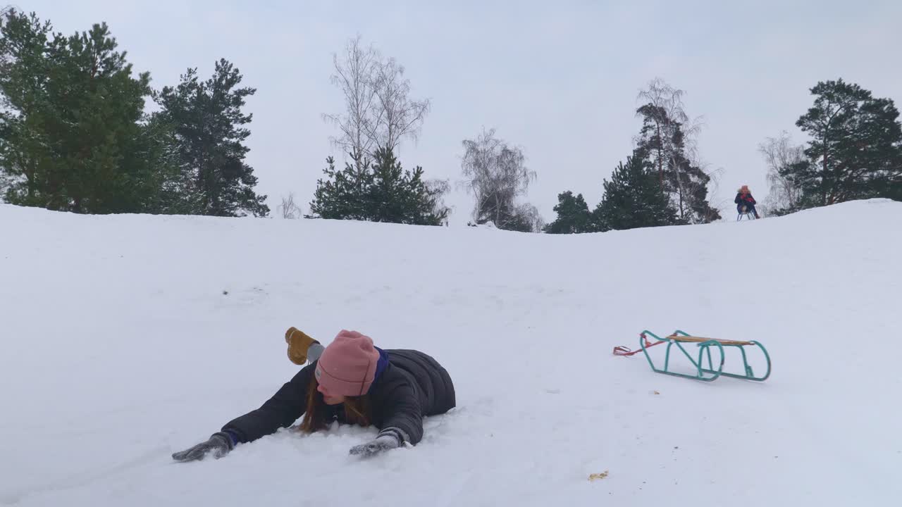 썰매를 탄 여자가 슬로우 모션으로 눈 위에 평평하게 떨어지는 모습