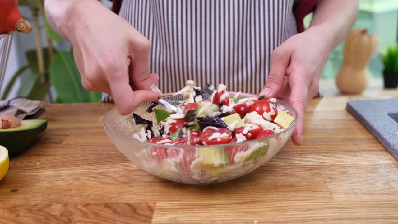 Casalinga mescola insalata tritata in una ciotola di vetro con un cucchiaio.