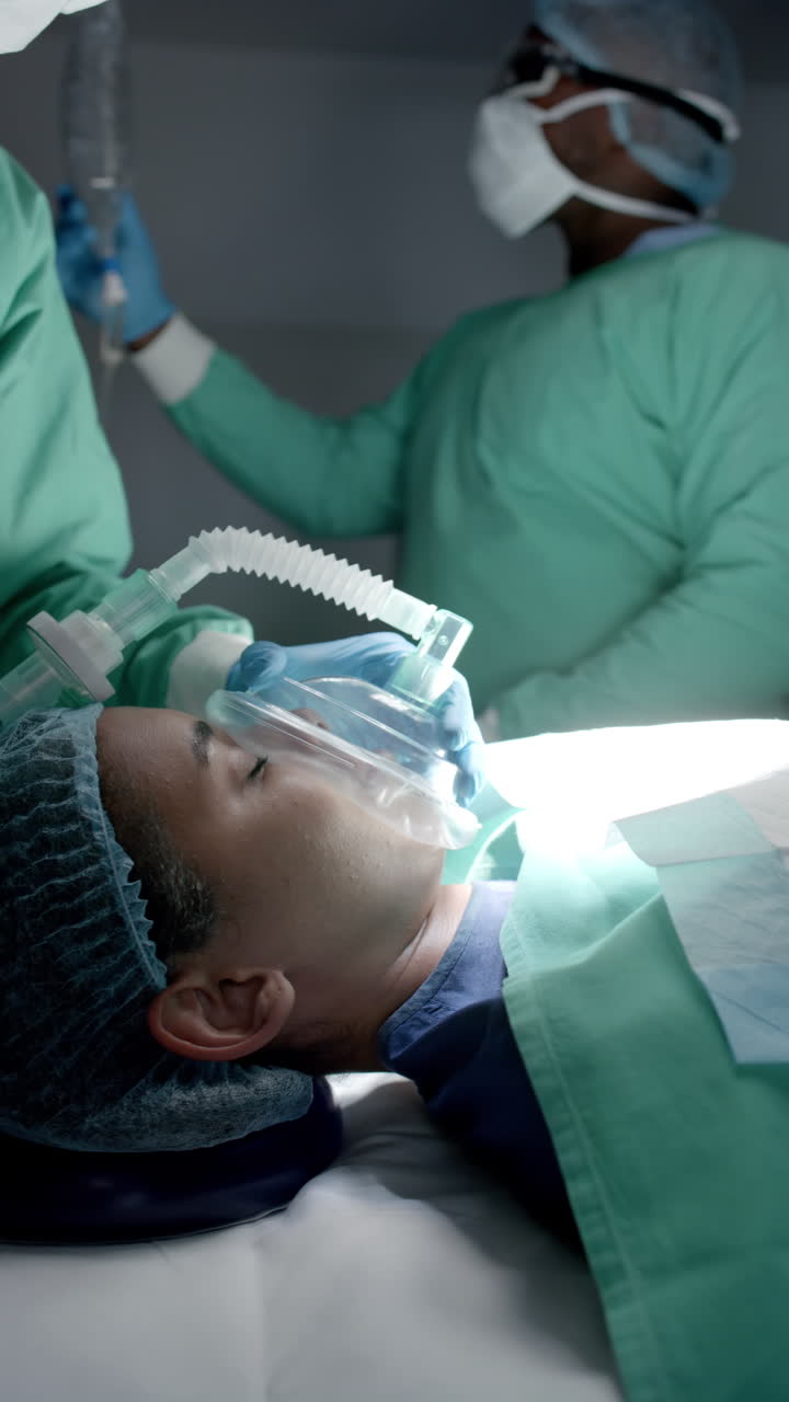 Vertical video of diverse surgeons with face masks using oxygen mask on patient in slow motion