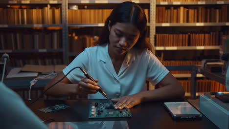 woman soldering circuit board in a workshop