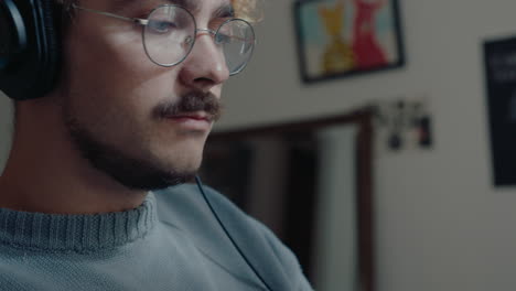 young musician in headphones playing synthesizer at home