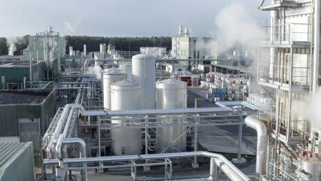 aerial drone navigates through sections of large factory, highlighting storage tanks, extensive pipe networks, and steam emissions, castets, france