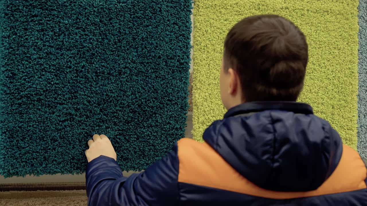 un joven elige una alfombra en la tienda de materiales de construcción con el propósito de comprar