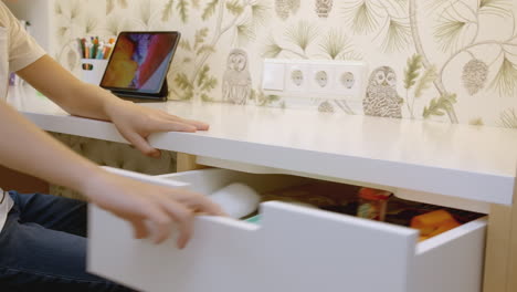 child opening a drawer at a desk in a bedroom