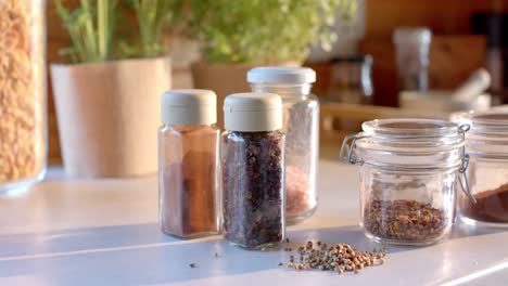 storage jars of seasonings on countertop in sunny kitchen, slow motion